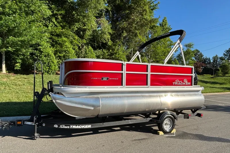 Slide: The Image of 2026 Sun Tracker Party Barge 16 DLX pontoon boat on trailer, parked outdoors. - 1