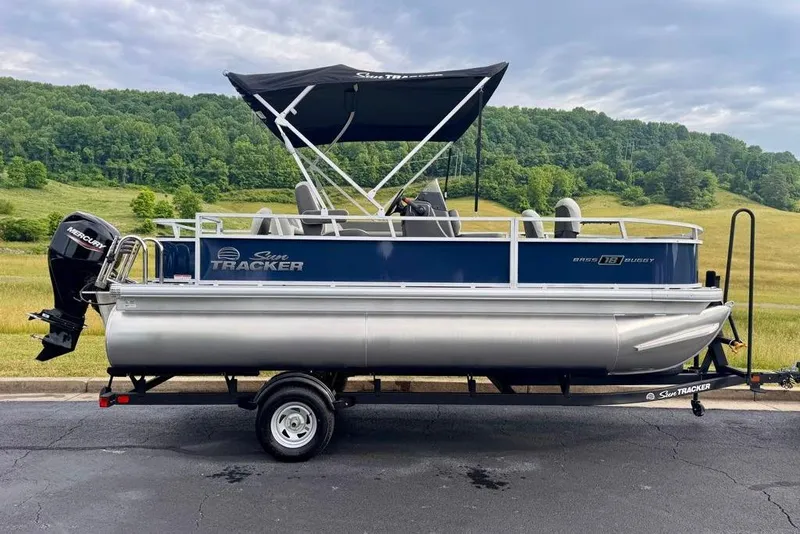 The Image of 2026 Sun Tracker Bass Buggy 18 DLX pontoon boat on trailer, scenic background. - 0