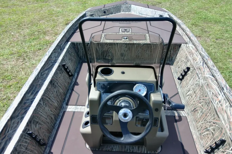 Slide: The Image of 2026 Tracker Grizzly 1860 CC boat interior with camouflage design and steering console. - 18