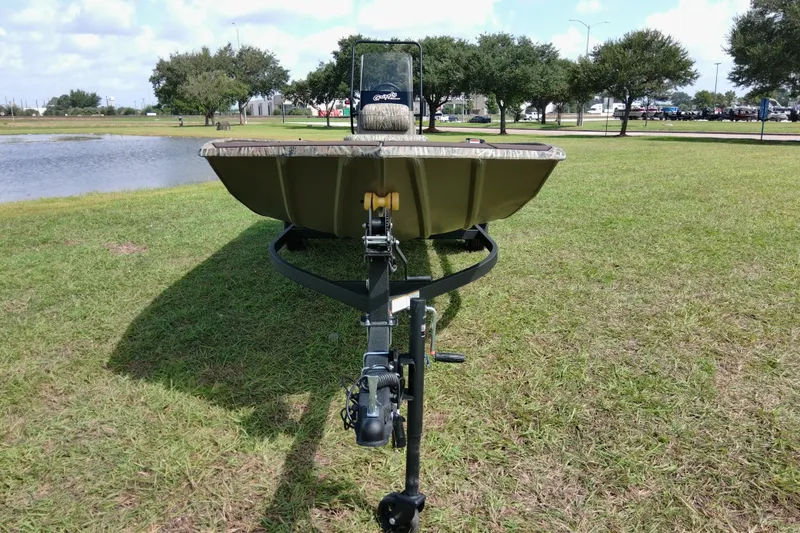 Slide: The Image of 2026 Tracker Grizzly 1860 CC boat on trailer, parked on grassy area near a pond. - 8