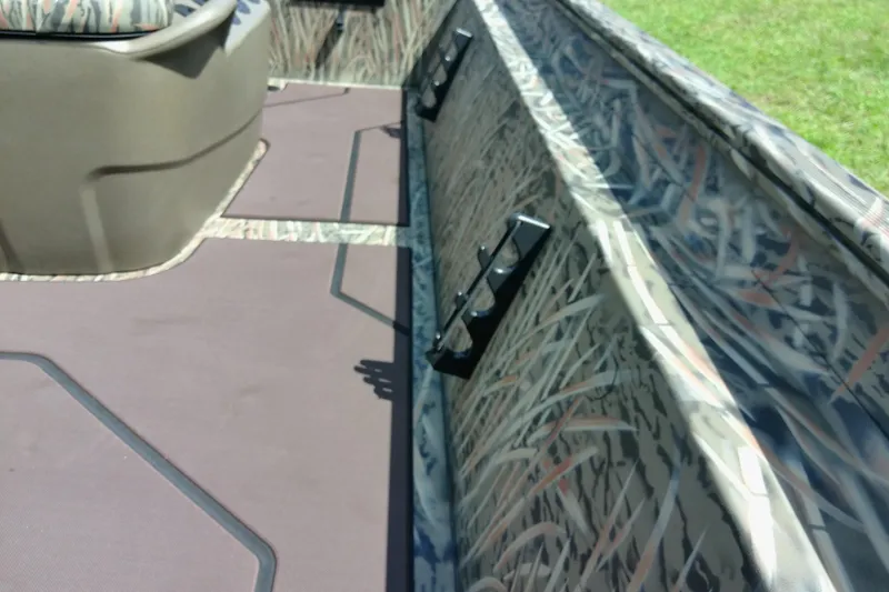 Slide: The Image of 2026 Tracker Grizzly 1860 CC boat interior with camouflage design and rod holders. - 23