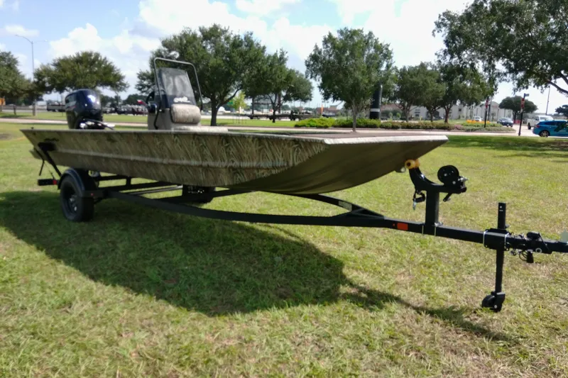 Slide: The Image of 2026 Tracker Grizzly 1860 CC boat on trailer, parked on grassy area with trees. - 15