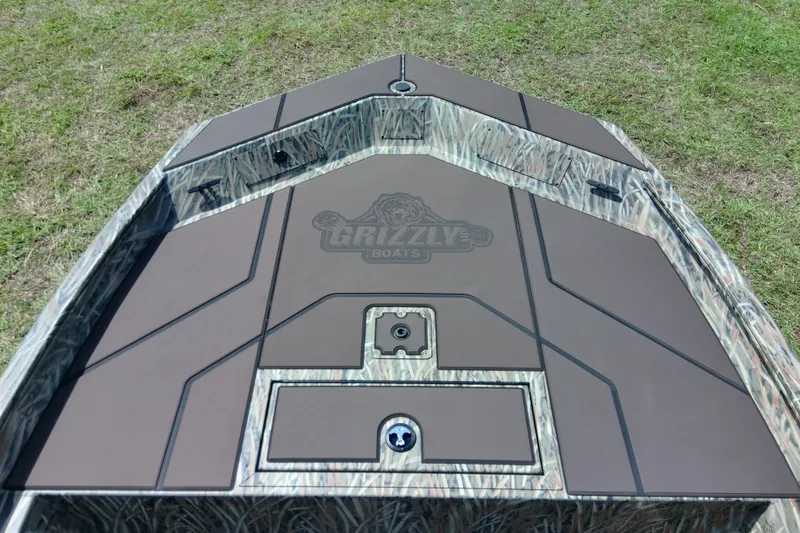 Slide: The Image of 2026 Tracker Grizzly 1860 CC boat deck with camo design on grass. - 19