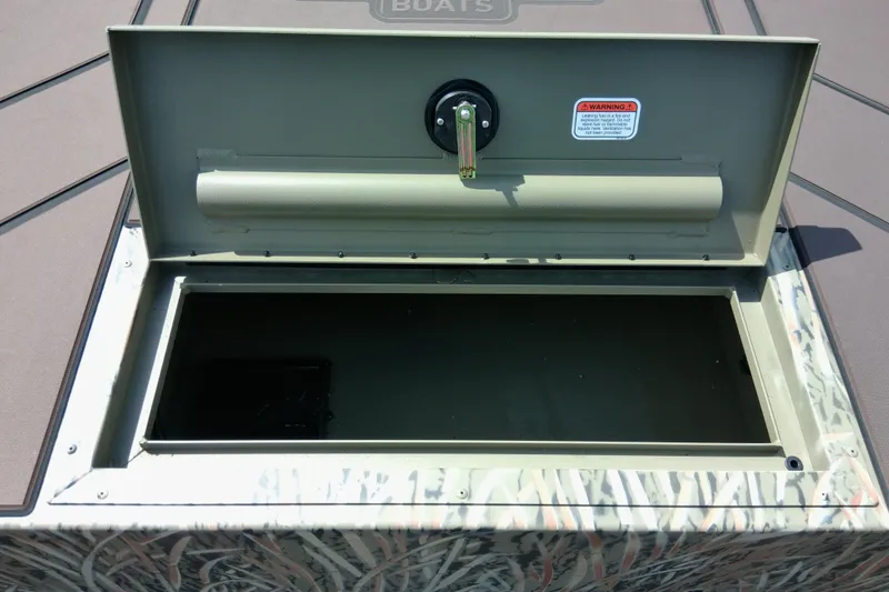 Slide: The Image of Open storage compartment on 2026 Tracker Grizzly 1860 CC boat, featuring camouflage design. - 21