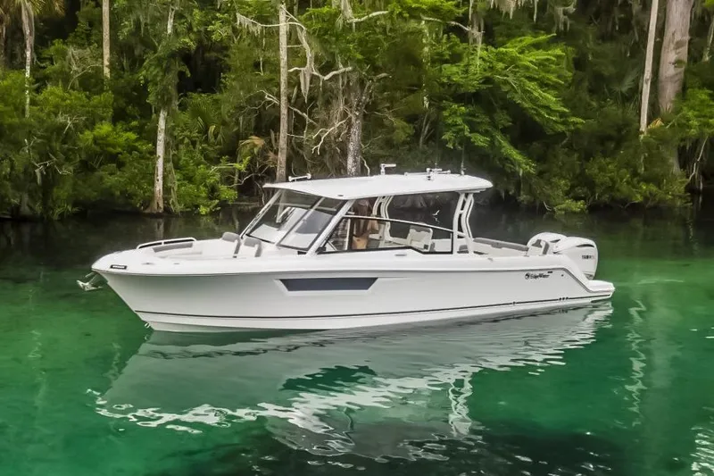The Image of 2026 Edgewater boat on clear water, surrounded by lush greenery. - 0