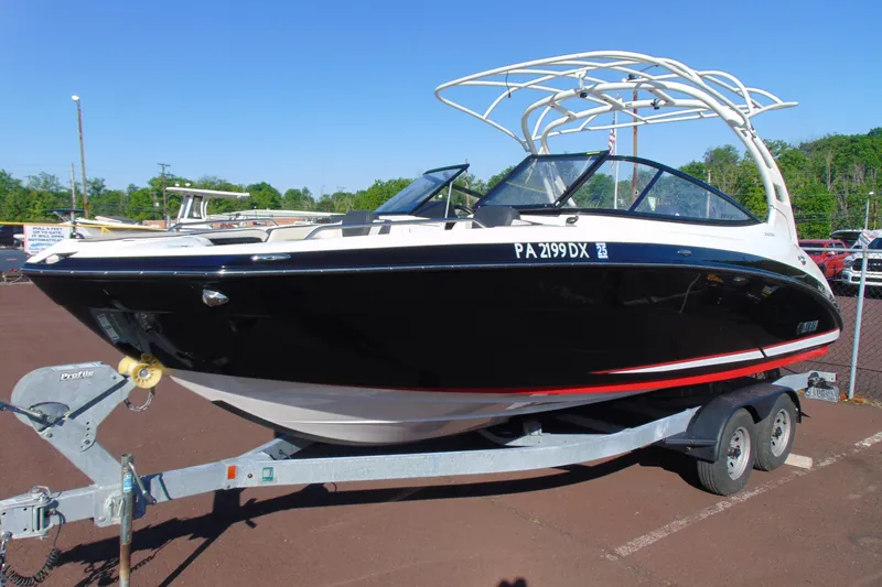 The Image of 2020 Yamaha Boats 242SE on trailer, black hull, parked outdoors. - 1