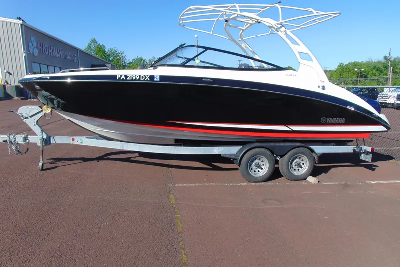 Slide: The Image of 2020 Yamaha Boats 242SE on trailer, black with red accents, parked at Highway Marine. - 2
