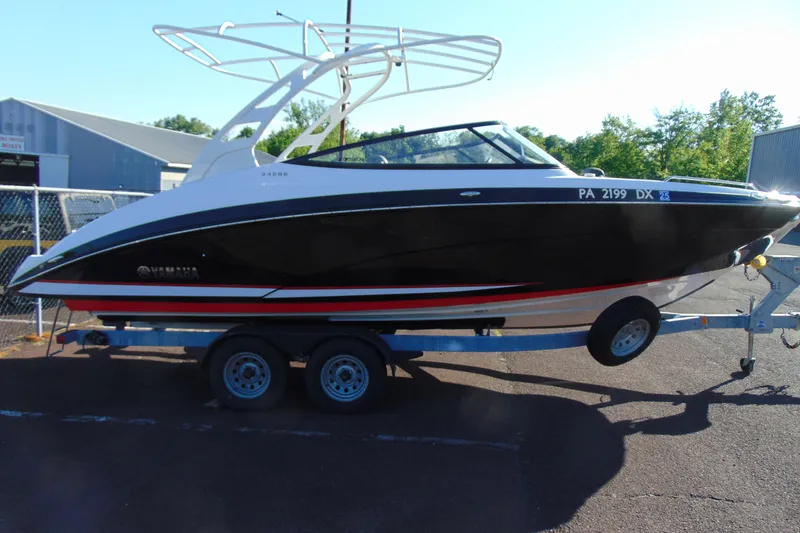 Slide: The Image of 2020 Yamaha Boats 242SE on trailer, sleek black design, parked outdoors. - 4