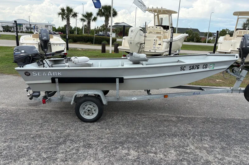 Slide: The Image of 2011 SeaArk 1448 MV boat on trailer, parked outdoors with palm trees in background. - 4