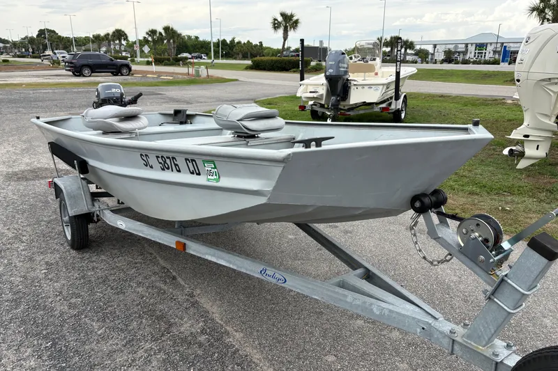Slide: The Image of 2011 SeaArk 1448 MV boat on trailer, parked outdoors with motor attached. - 5