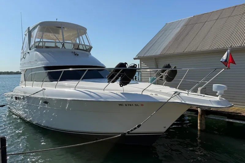 The Image of 2001 Silverton 42 Convertible yacht docked by a boathouse on a sunny day. - 0