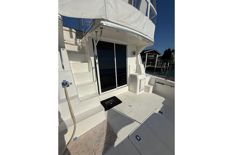 Slide: The Image of 2001 Silverton 42 Convertible yacht deck with stairs, sliding door, and marina view. - 12