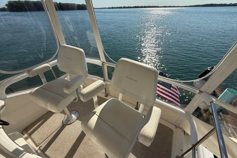 Slide: The Image of 2001 Silverton 42 Convertible boat interior with two white captain chairs overlooking water. - 23