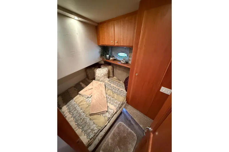 Slide: The Image of Cozy bedroom interior of 2001 Silverton 42 Convertible yacht with wooden cabinets and soft bedding. - 42