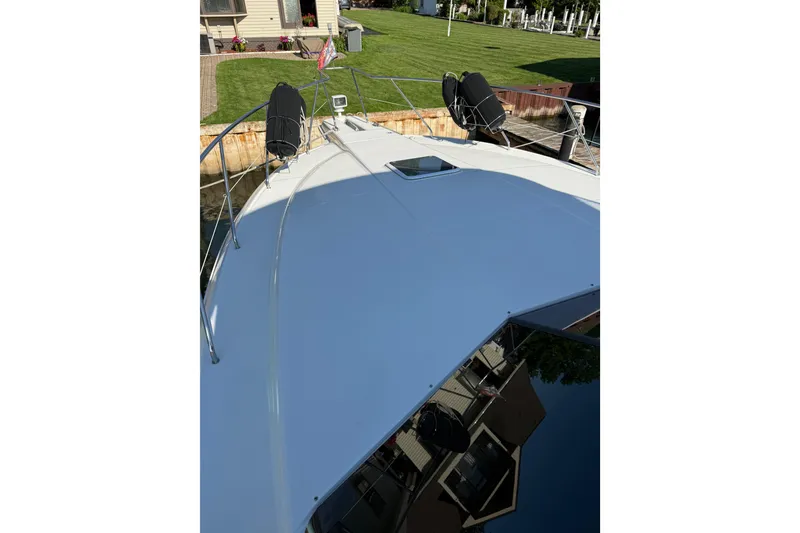 Slide: The Image of 2001 Silverton 42 Convertible yacht deck with docked view and lush green surroundings. - 7