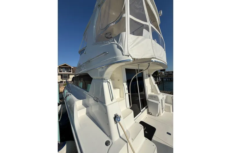 Slide: The Image of 2001 Silverton 42 Convertible yacht docked, featuring spacious deck and flybridge enclosure. - 8
