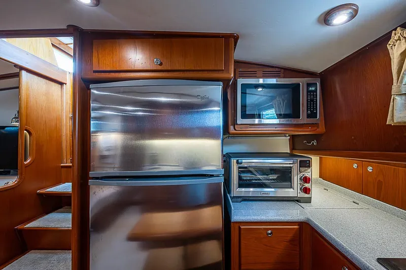 Slide: The Image of 2004 Grand Banks 49 Eastbay HX yacht kitchen with stainless steel appliances and wooden cabinetry. - 19