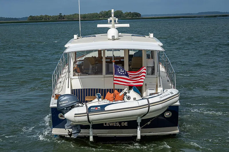 Slide: The Image of 2004 Grand Banks 49 Eastbay HX yacht with American flag and dinghy on water. - 4