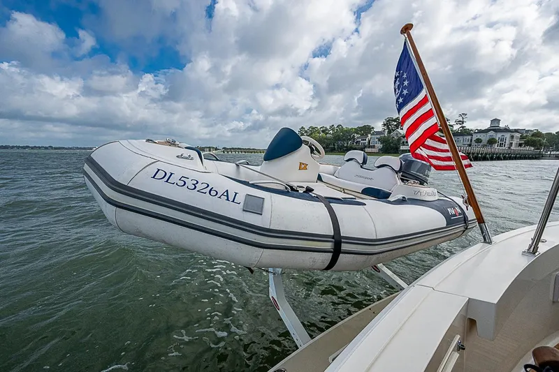 Slide: The Image of 2004 Grand Banks 49 Eastbay HX with dinghy and American flag on water. - 40