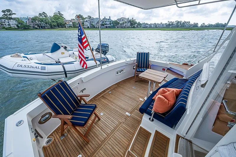 Slide: The Image of 2004 Grand Banks 49 Eastbay HX yacht deck with seating, table, and American flag. - 6