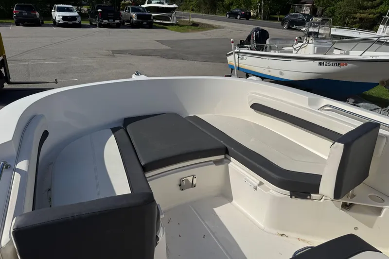 Slide: The Image of 2021 Trophy T22CX boat interior with cushioned seating in a parking lot setting. - 14