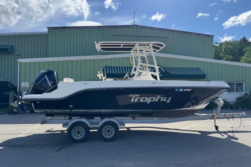 Slide: The Image of 2021 Trophy T22CX boat on trailer, parked outside a green building under a blue sky. - 3