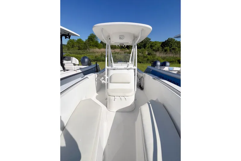 Slide: The Image of 2013 Tidewater 230 CC Adventure boat interior with seating and console, under clear blue sky. - 9