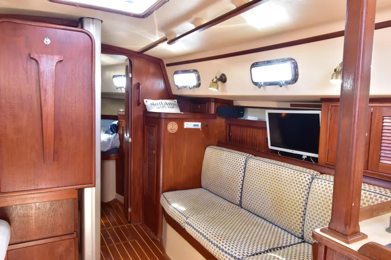 Slide: The Image of Interior of 1995 Island Packet 37 sailboat with cozy seating and wooden cabinetry. - 11