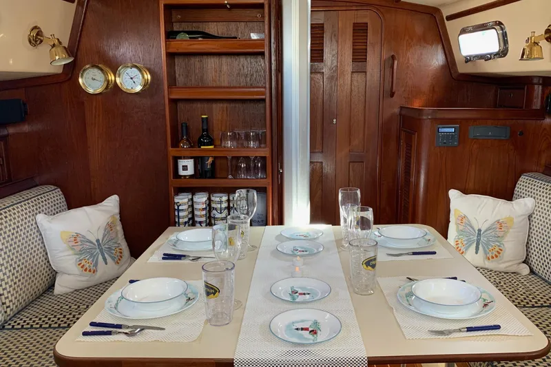 Slide: The Image of Elegant dining setup in a 1995 Island Packet 37 sailboat interior, featuring butterfly-themed decor. - 12