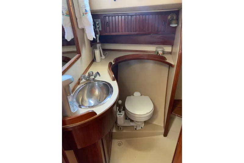 Slide: The Image of 1995 Island Packet 37 yacht bathroom with sink and toilet, featuring wooden accents. - 14
