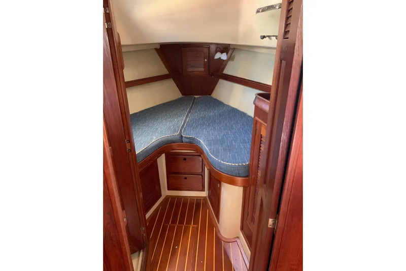 Slide: The Image of 1995 Island Packet 37 sailboat cabin with wooden interior and blue cushioned berth. - 16