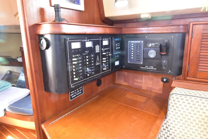 Slide: The Image of Electrical control panel on a 1995 Island Packet 37 sailboat, featuring wood finish and switches. - 17