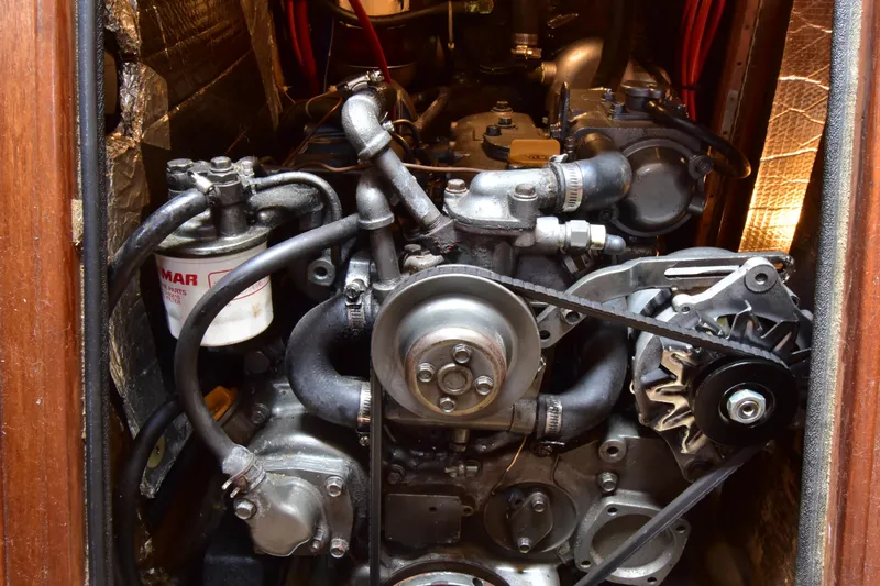 Slide: The Image of Engine compartment of a 1995 Island Packet 37 sailboat, showcasing mechanical components and wiring. - 18
