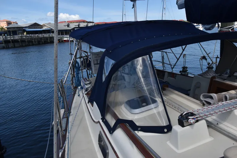 Slide: The Image of 1995 Island Packet 37 sailboat docked, featuring a blue canopy and marina backdrop. - 4