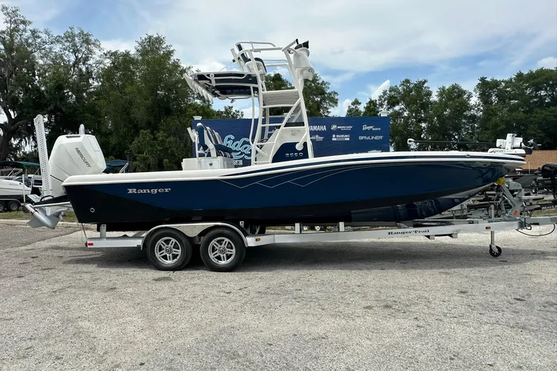 The Image of 2026 Ranger 2660 Bay boat on trailer, parked outdoors with trees in background. - 0