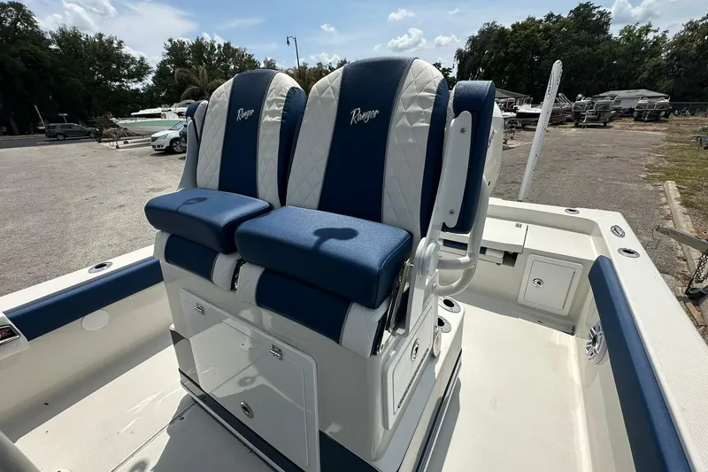 Slide: The Image of 2026 Ranger 2660 Bay boat with blue and white seating in a parking area. - 21