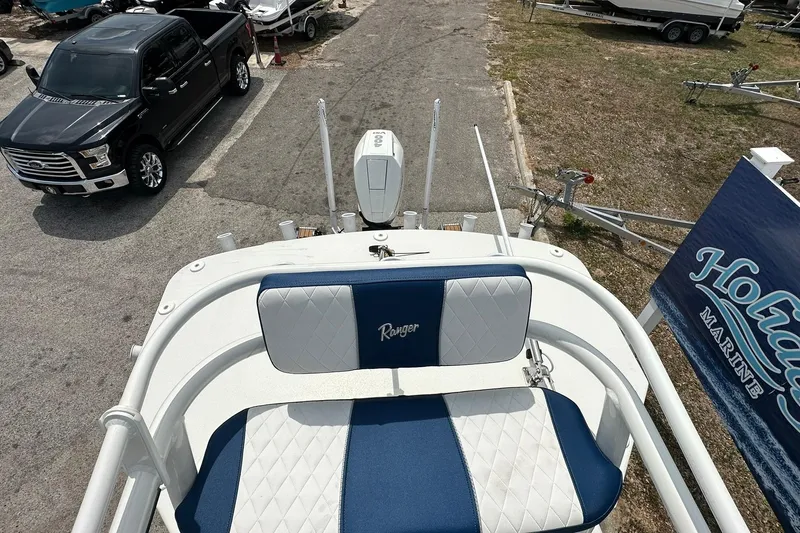 Slide: The Image of 2026 Ranger 2660 Bay boat with blue and white seating, parked near a black truck. - 42
