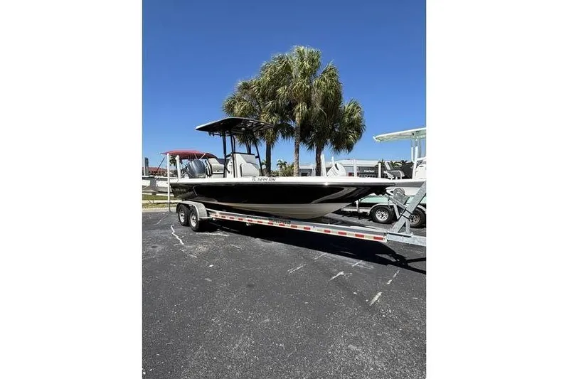 The Image of 2018 ShearWater 25 LTD boat on trailer, parked near palm trees under clear blue sky. - 3