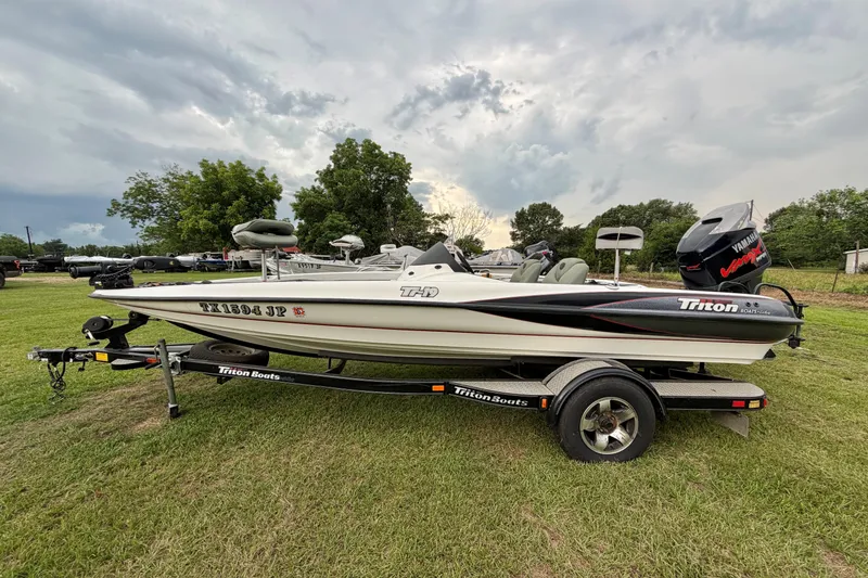 The Image of 2001 Triton Tr-19 boat on trailer, parked on grassy field under cloudy sky. - 1