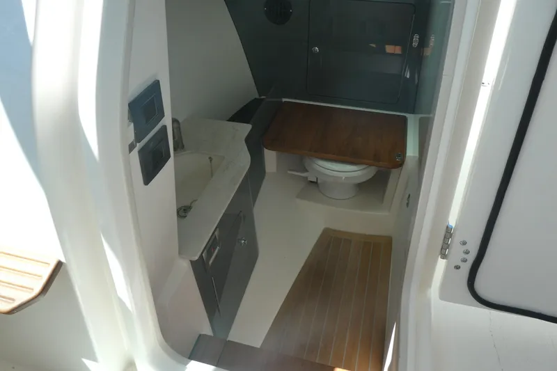 Slide: The Image of Interior of 2026 Boston Whaler 330 Vantage boat, featuring a compact bathroom with sink and toilet. - 11