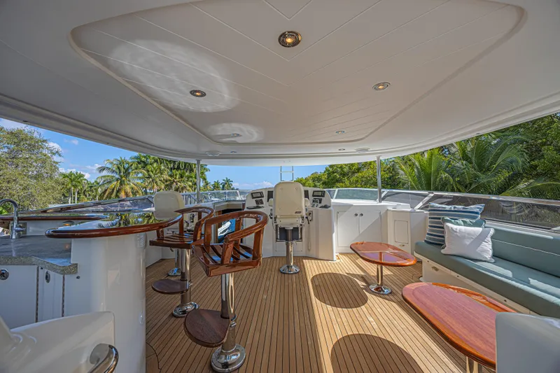 Slide: The Image of Luxurious 2011 Westport 112 yacht deck with seating, bar, and helm, surrounded by tropical scenery. - 11