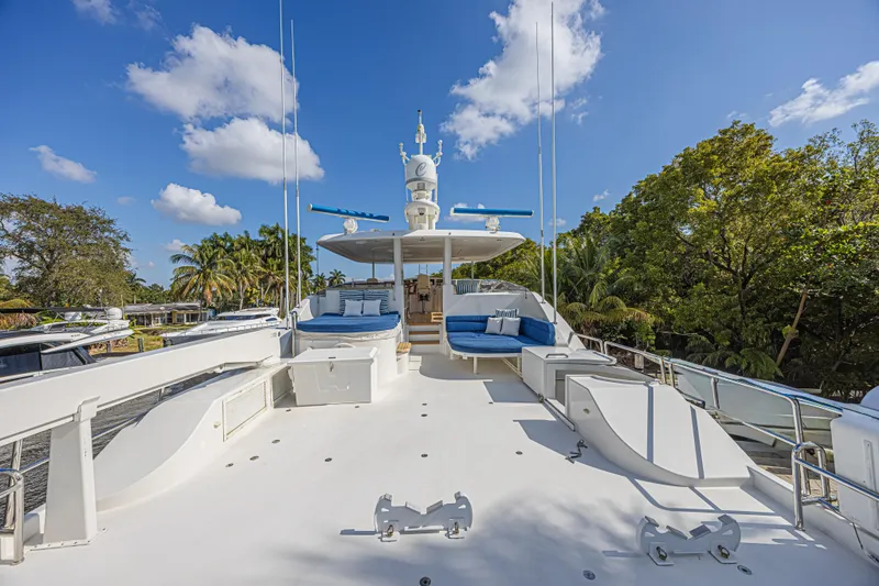 Slide: The Image of Luxurious 2011 Westport 112 yacht deck with seating, surrounded by lush greenery and blue sky. - 5