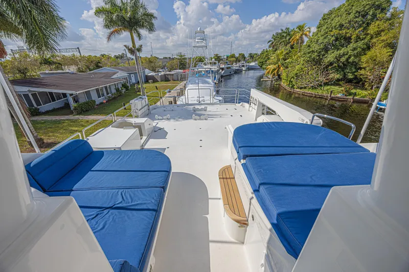 Slide: The Image of Luxurious 2011 Westport 112 yacht deck with blue seating, docked by a scenic canal. - 6
