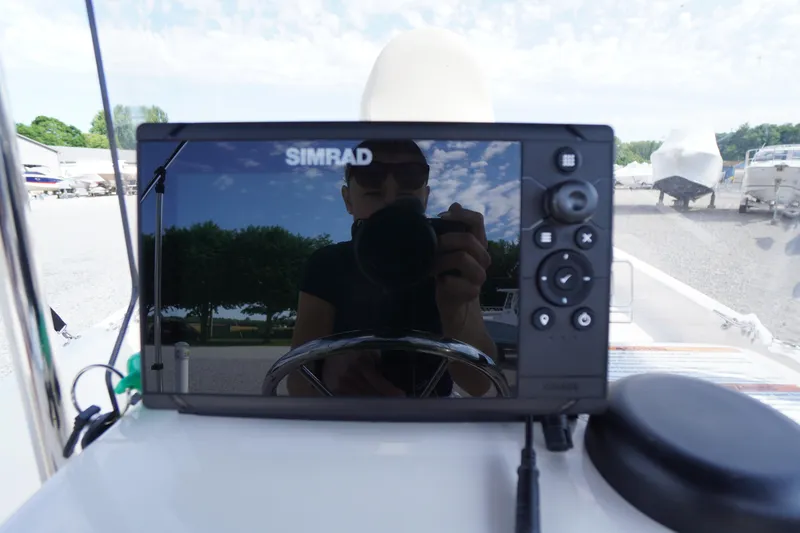 Slide: The Image of Simrad navigation system on 2024 Carolina Skiff 182 boat, reflecting outdoor scenery. - 24