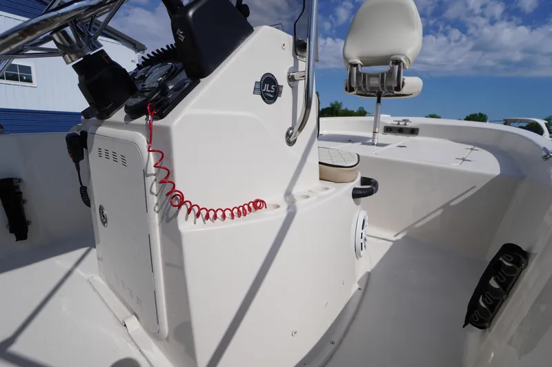 Slide: The Image of 2024 Carolina Skiff 182 boat console with steering wheel and seating under blue sky. - 29