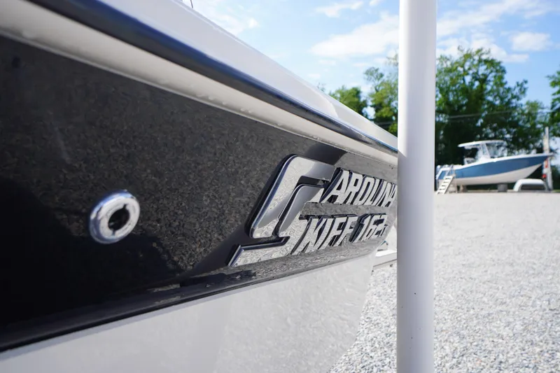 Slide: The Image of 2024 Carolina Skiff 182 boat side view with logo, parked outdoors. - 3