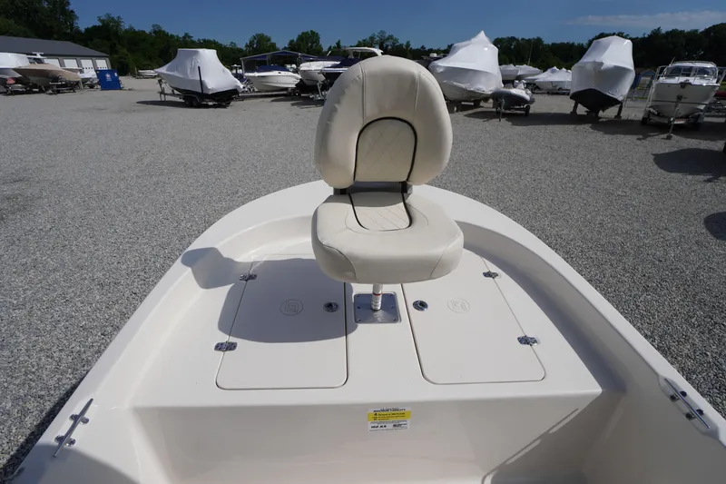 Slide: The Image of 2024 Carolina Skiff 182 boat with a cushioned seat, displayed in a gravel lot. - 35