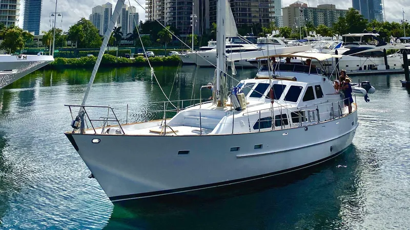 The Image of 1990 Cheoy Lee Sloop sailing in a marina with city skyline background. - 1