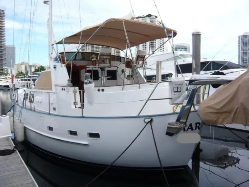 Slide: The Image of 1990 Cheoy Lee Sloop docked at marina, featuring a spacious deck and canopy. - 5