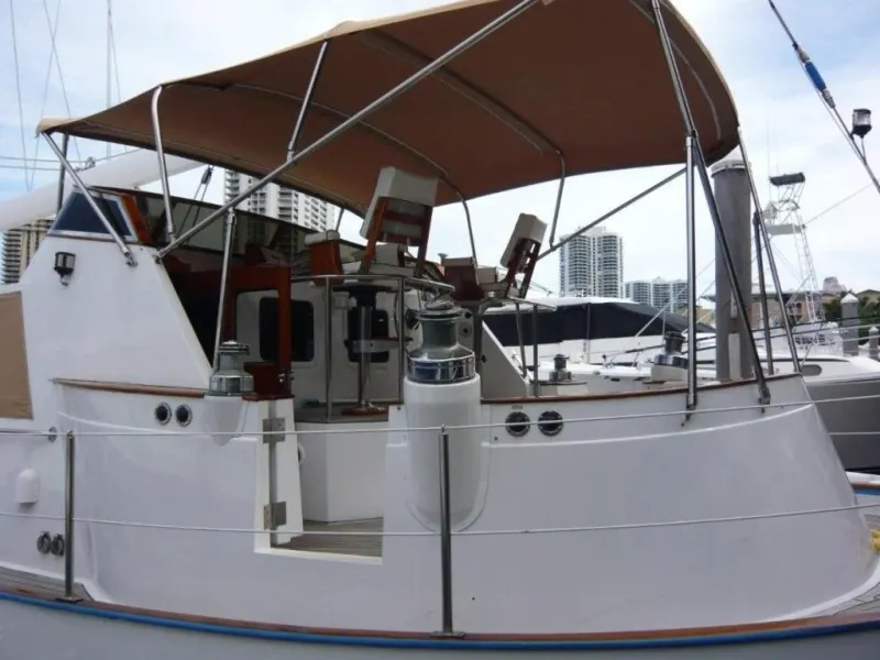 Slide: The Image of 1990 Cheoy Lee Sloop with canopy, docked in marina, city skyline in background. - 7